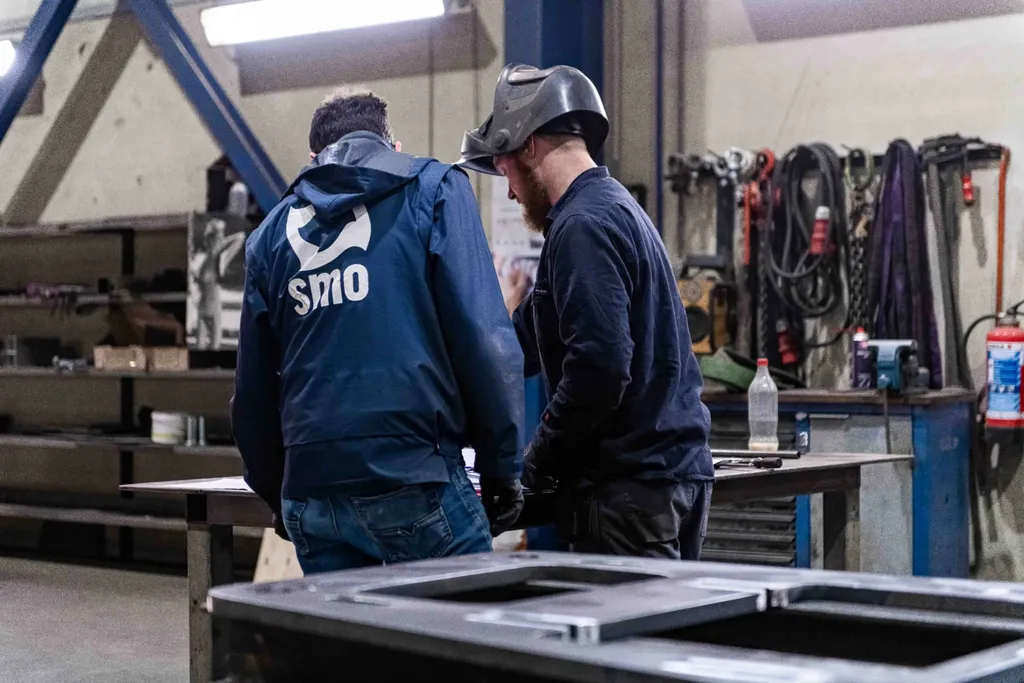 DESMO-rek in de werkplaats van SMO, met mensen aan het werk